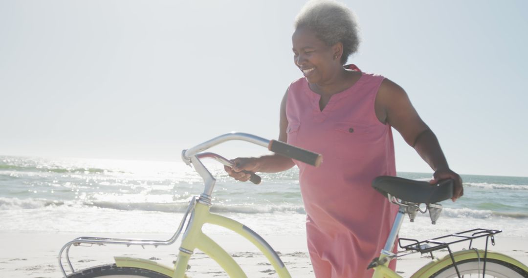 Happy Elderly Woman with Bicycle Strolling on Sandy Beach - Free Images, Stock Photos and Pictures on Pikwizard.com