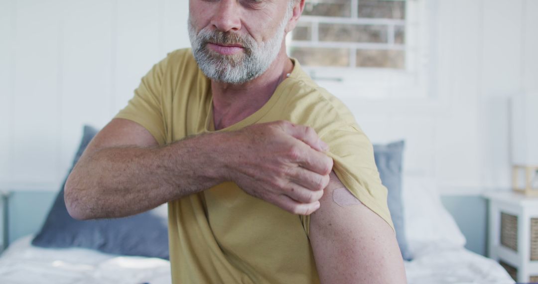 Middle-aged man showing adhesive patch on arm at home - Free Images, Stock Photos and Pictures on Pikwizard.com