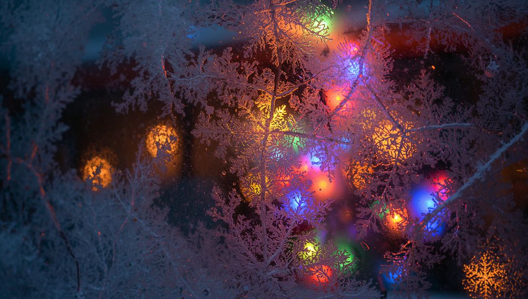 Frosted Windowpane Showing Ice Crystal Patterns with Multicolor Holiday Lights Bokeh