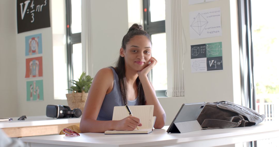 High School Student Using Tablet and Notepad in Modern Classroom