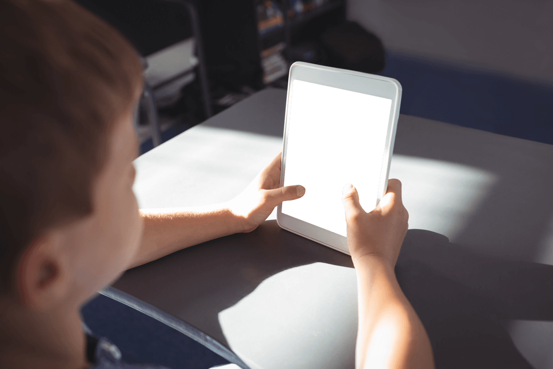 Transparent Screen Tablet Used by Curious Child Seating at Desk