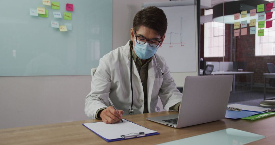 Asian Doctor Wearing Mask Working in Medical Office - Free Images, Stock Photos and Pictures on Pikwizard.com