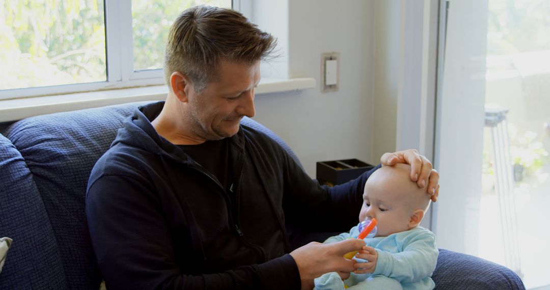 Father Gently Feeding Baby with Spoon in Cozy Home Setting - Free Images, Stock Photos and Pictures on Pikwizard.com