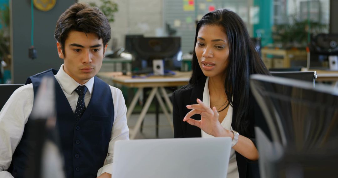 Professionals Collaborating in Open Plan Office with Laptop