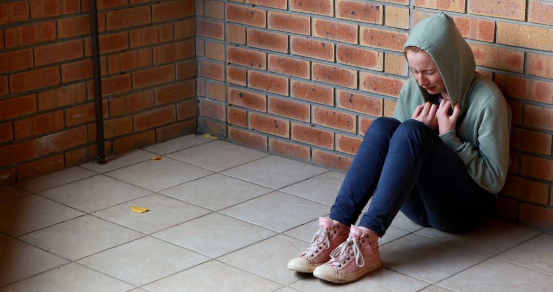 Sad Teen Girl Sitting Alone Against Brick Wall - Free Images, Stock Photos and Pictures on Pikwizard.com