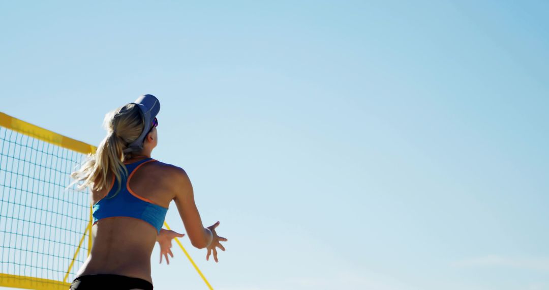 Female Beach Volleyball Player Reaching at Net Under Clear Blue Sky With Spacious Copy Area