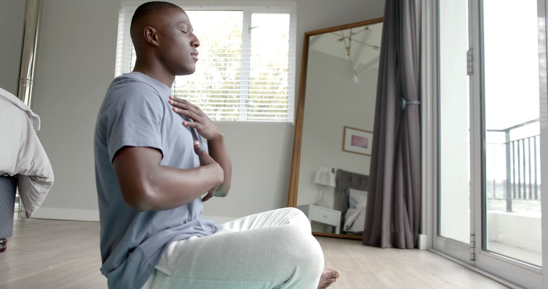 Man Meditating in Sunlit Bedroom for Relaxation and Mindfulness - Free Images, Stock Photos and Pictures on Pikwizard.com