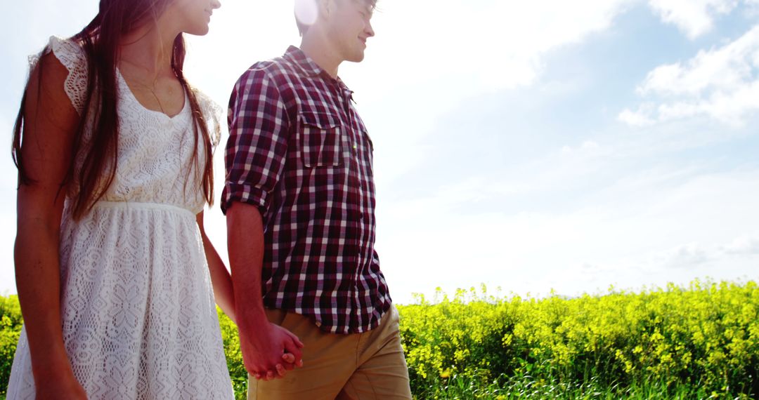 Young Couple Holding Hands and Walking in Sunlit Countryside - Free Images, Stock Photos and Pictures on Pikwizard.com