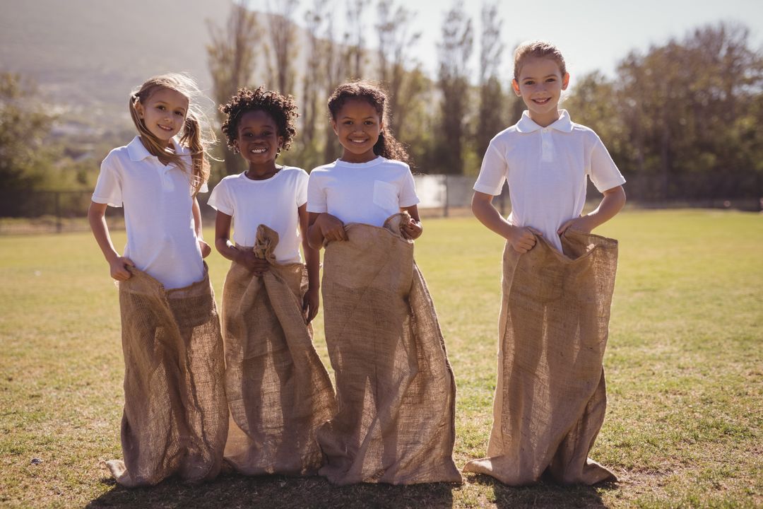 Portrait of happy schoolgirls standing in sack during race - Free Images, Stock Photos and Pictures on Pikwizard.com