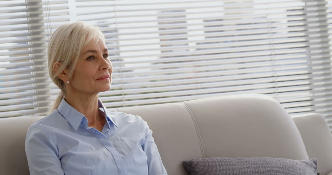 Senior Woman Sitting on Sofa in Modern Office Lounge - Free Images, Stock Photos and Pictures on Pikwizard.com