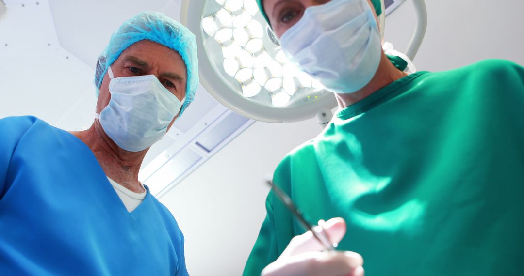 Surgeons performing a procedure in operating room under bright lights - Free Images, Stock Photos and Pictures on Pikwizard.com