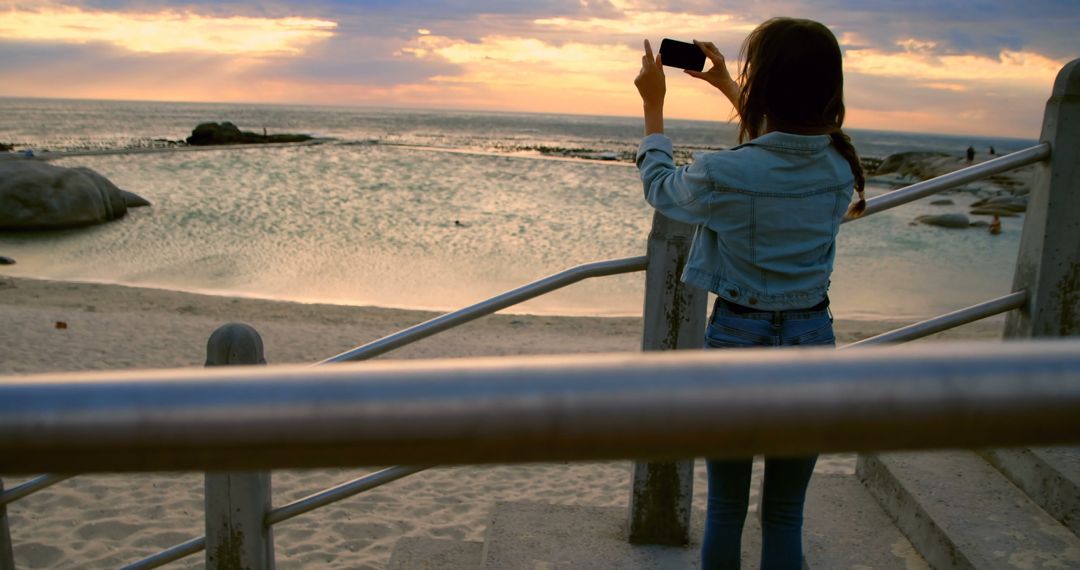 Woman capturing sunset on beach using smartphone - Free Images, Stock Photos and Pictures on Pikwizard.com