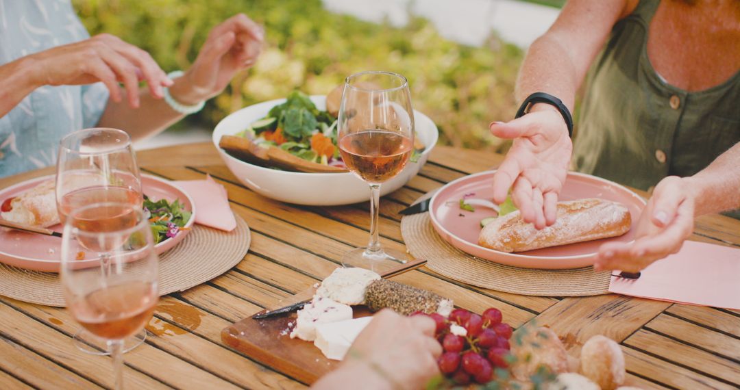Friends Enjoying Outdoor Meal with Wine and Cheese Platter