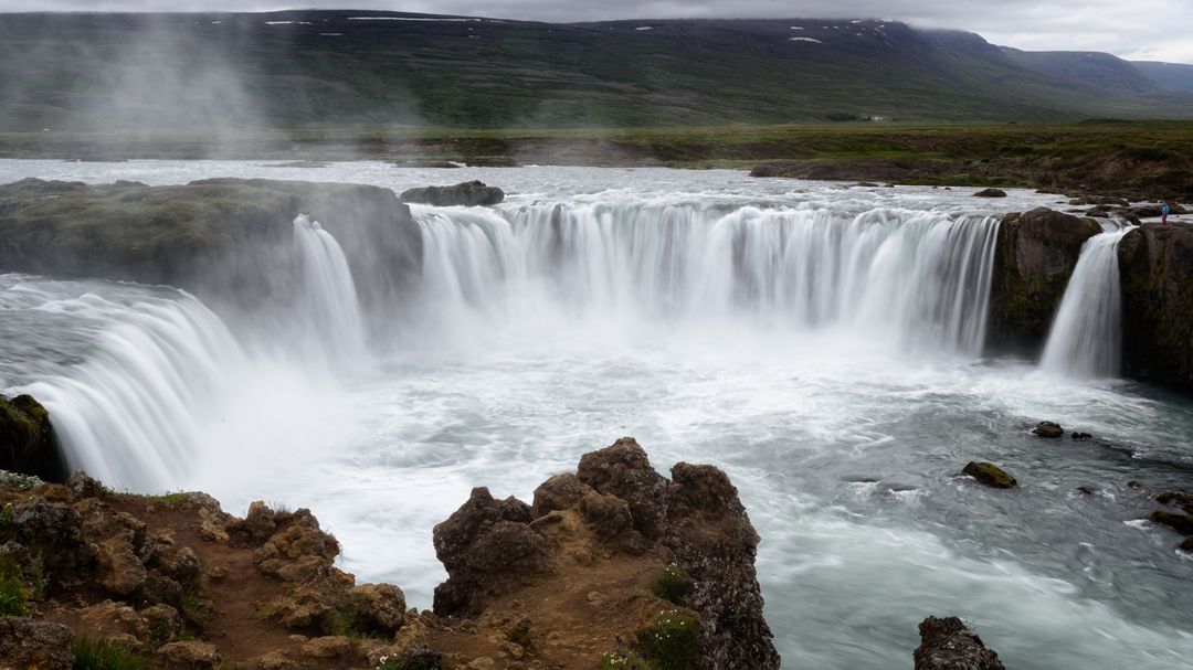 Cascading Godafoss waterfall with misty basalt cliffs in Icelandic volcanic landscape