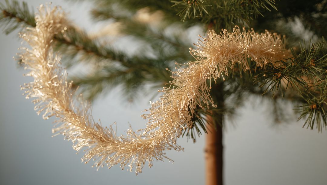 Gold Tinsel Garland Looping on Pine Branch with Sparkling Filament Tips Macro