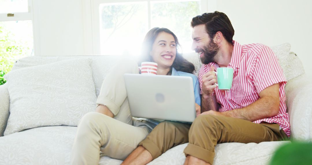 Couple Relaxing on Couch with Hot Beverages and Tablet