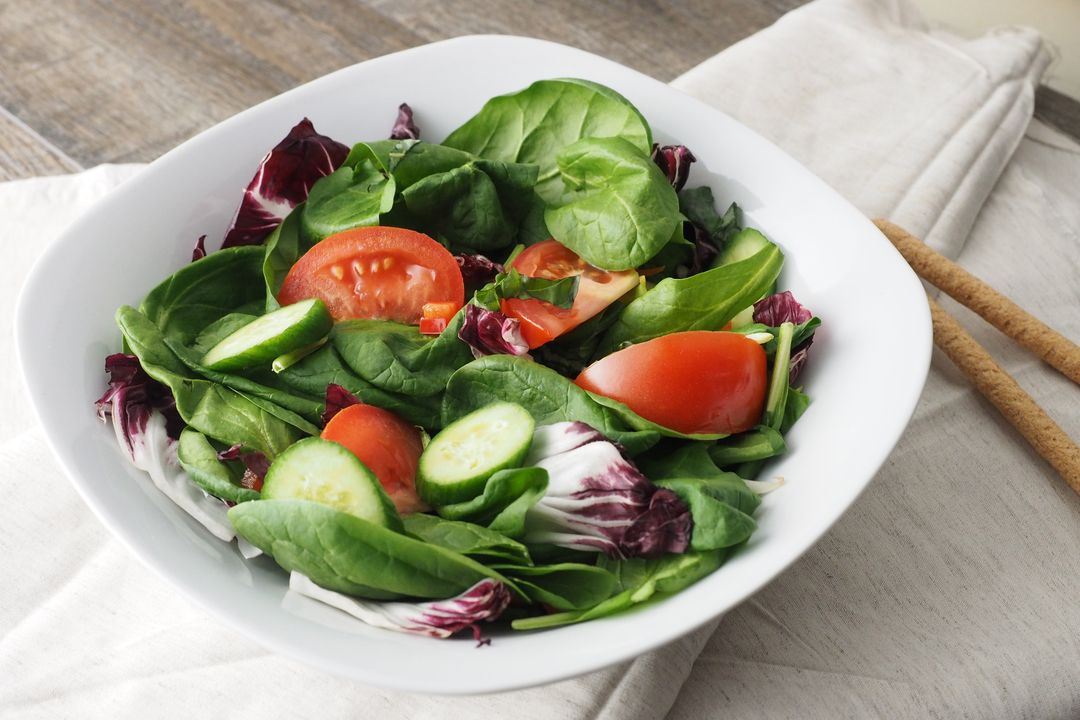 Fresh spinach and radicchio salad with tomato and cucumber in white bowl for healthy menu