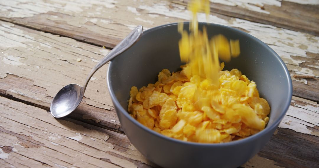 Pouring Cornflakes into Bowl on Rustic Wooden Table - Free Images, Stock Photos and Pictures on Pikwizard.com