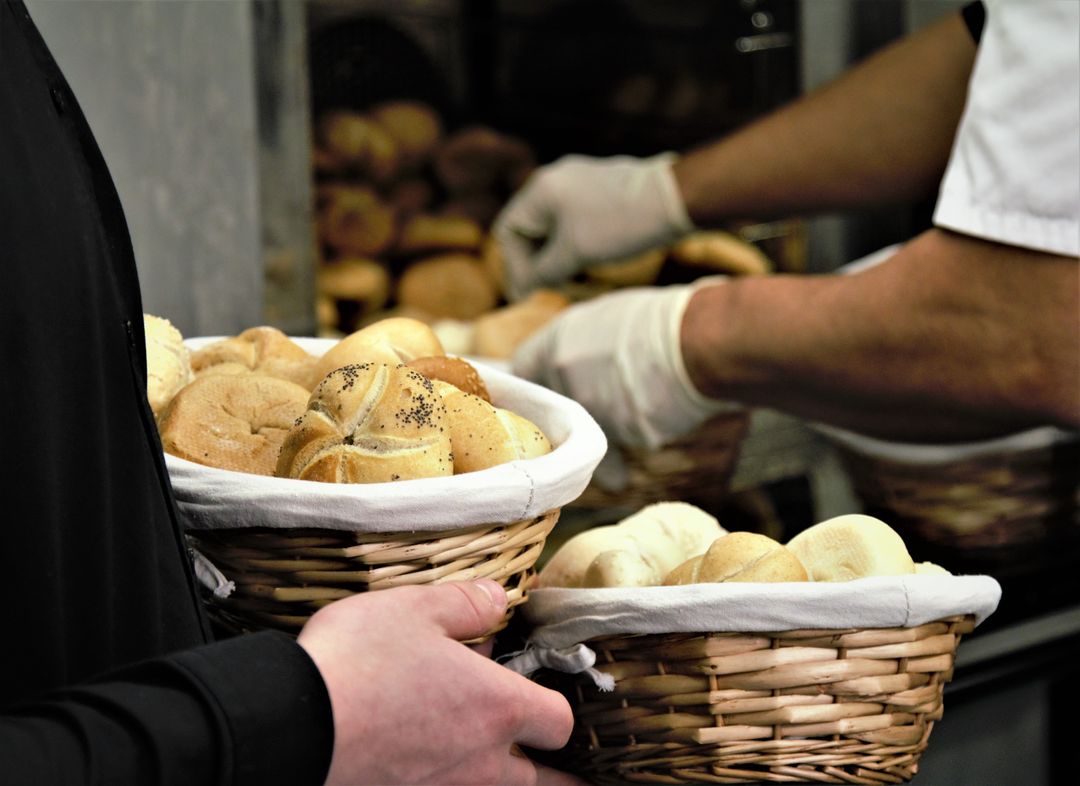 Baker Handling Freshly Baked Bread Rolls in Wicker Baskets
