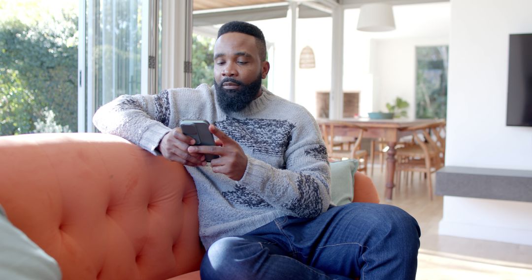 African American Man Relaxing on Sofa Using Smartphone at Home - Free Images, Stock Photos and Pictures on Pikwizard.com