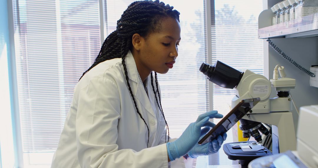 Scientist Using Digital Tablet While Examining Sample in Laboratory