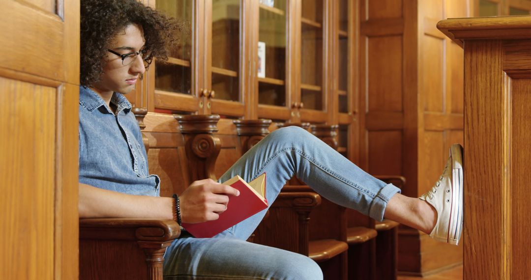 Young Man Reading Book in Library, Focusing on Study