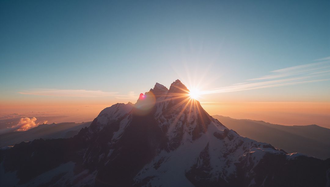 Sunrise Illuminating Snow-Capped Mountain Peak with Lens Flare