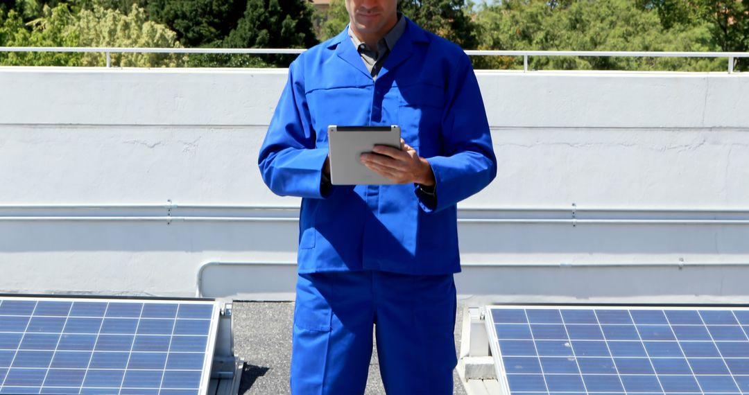 Engineer in blue uniform using tablet near solar panels - Free Images, Stock Photos and Pictures on Pikwizard.com