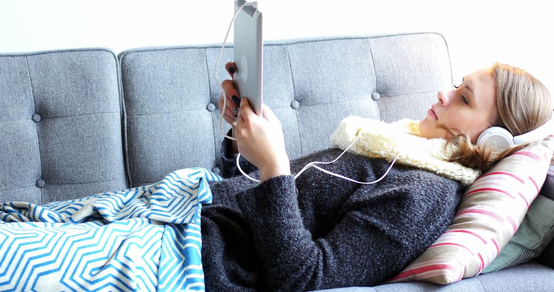 Woman Relaxing on Sofa Using Tablet with Headphones - Free Images, Stock Photos and Pictures on Pikwizard.com