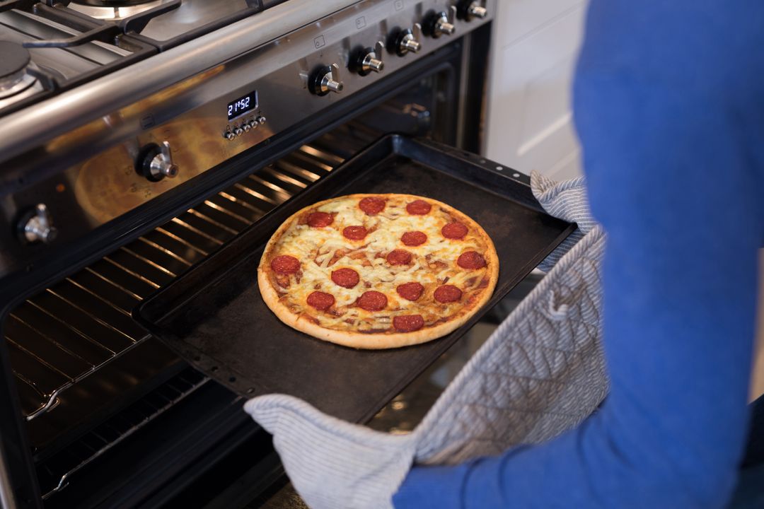Man putting pizza into oven in kitchen - Free Images, Stock Photos and Pictures on Pikwizard.com