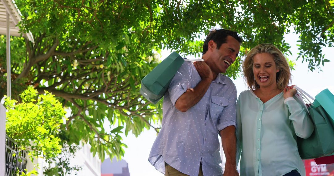 Couple Smiling While Shopping Outdoors with Green Bags - Free Images, Stock Photos and Pictures on Pikwizard.com