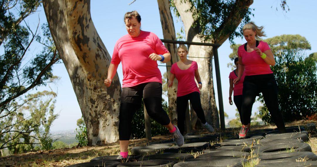 Women in Pink Shirts Navigating Outdoor Obstacle Course with Tires - Free Images, Stock Photos and Pictures on Pikwizard.com