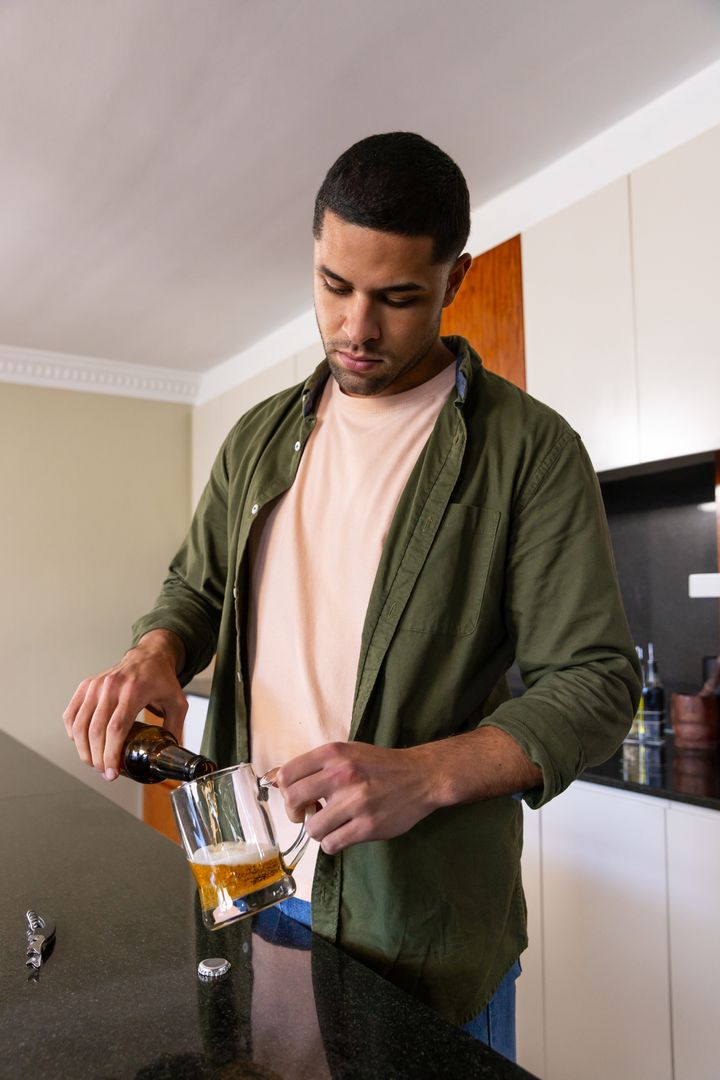 Man Pouring Beer into Glass Mug at Home Kitchen