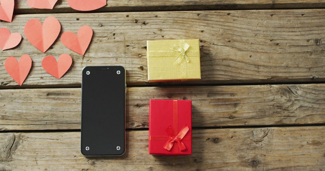 Valentine's Day Gifts with Hearts and Smartphone on Rustic Wooden Background
