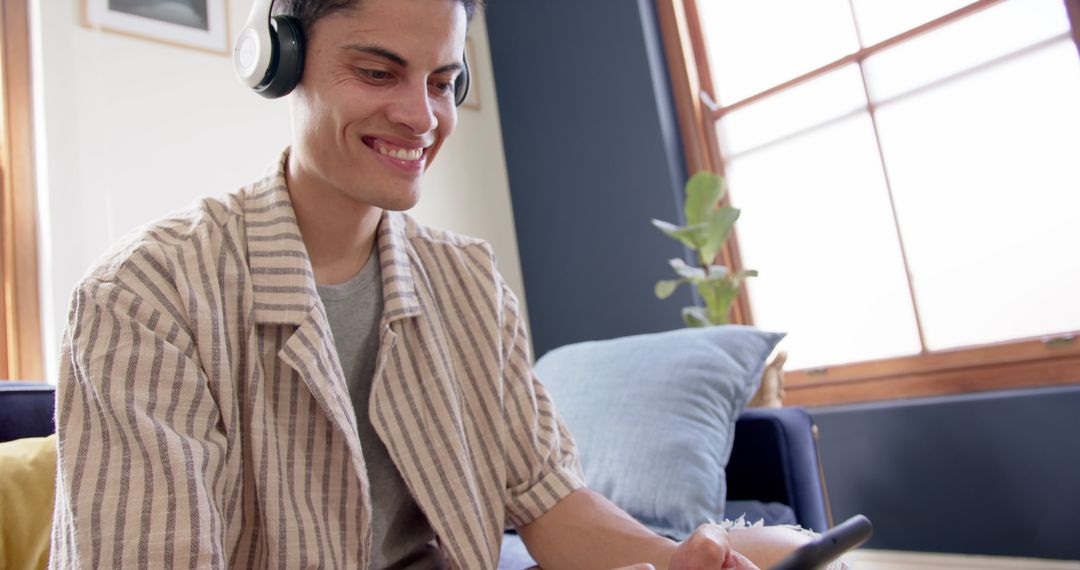 Man Relaxing with Headphones While Using Smartphone at Home