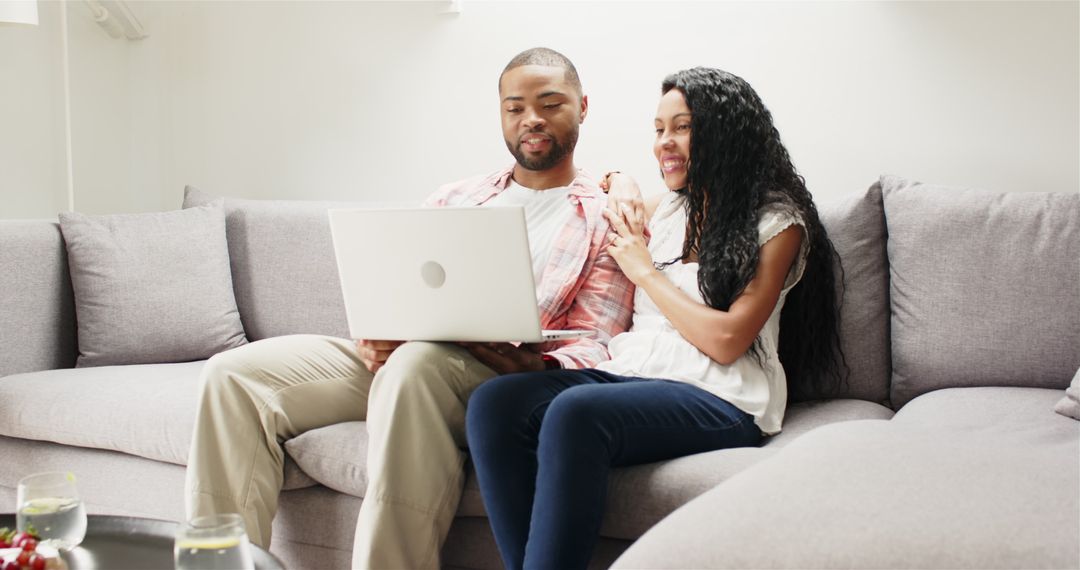 Joyful Couple Relaxing at Home Using Laptop on Couch