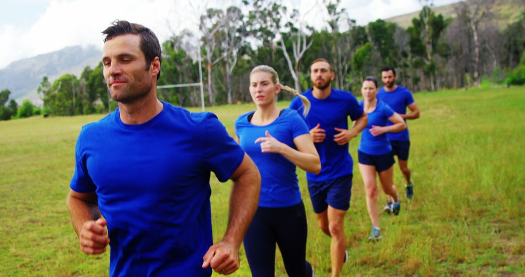 Group of People Wearing Blue Activewear Running in a Green Field - Free Images, Stock Photos and Pictures on Pikwizard.com