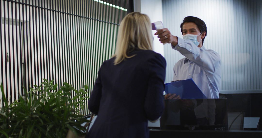 Caucasian businessman wearing face mask checking coworkers temperature - Free Images, Stock Photos and Pictures on Pikwizard.com