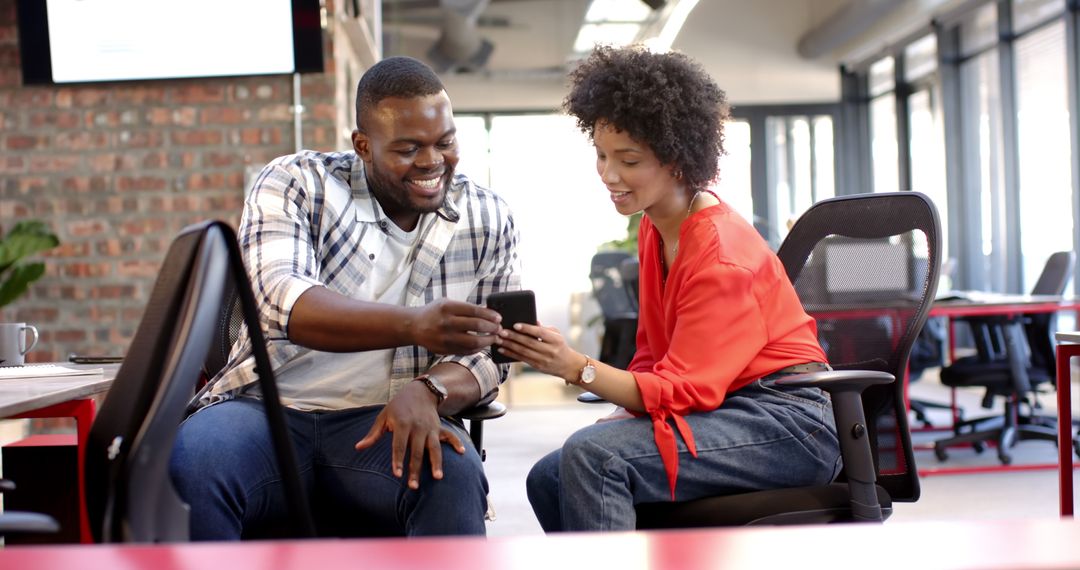 Young Business Colleagues Discussing Ideas Over Smartphone with Enthusiasm