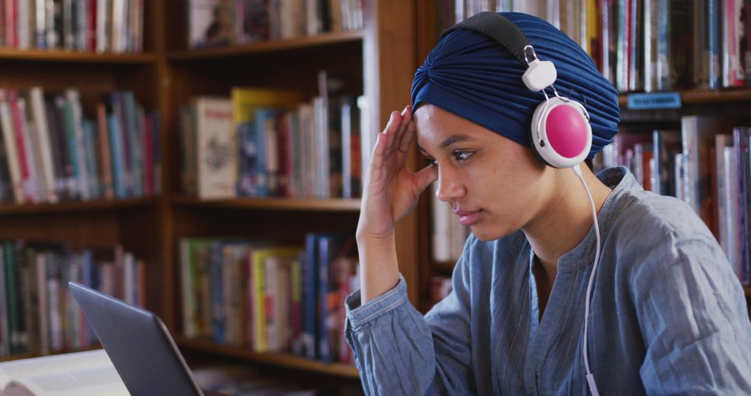 Young Woman Studying in Library Wearing Blue Hijab and Listening to Music - Free Images, Stock Photos and Pictures on Pikwizard.com