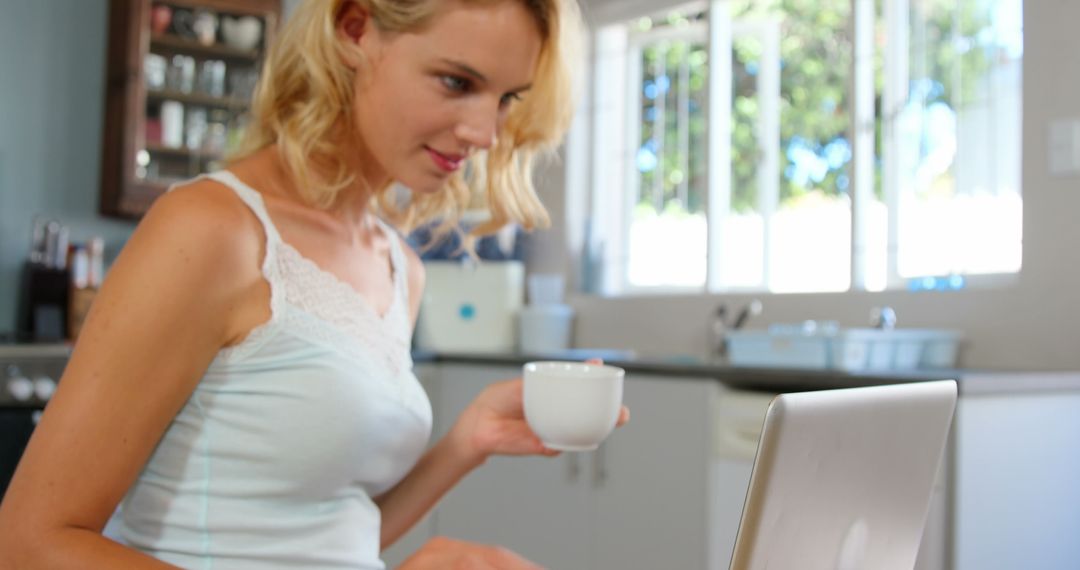 Woman Working on Laptop at Home While Holding Coffee Cup - Free Images, Stock Photos and Pictures on Pikwizard.com