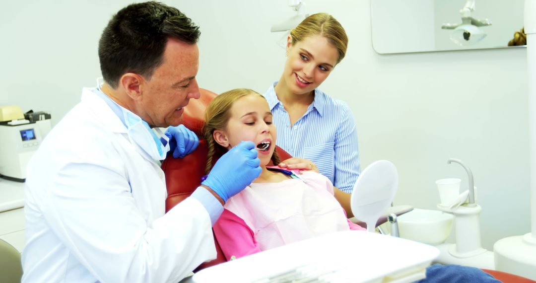 Dentist Examining Girl's Teeth as Mother Observes in Dental Clinic - Free Images, Stock Photos and Pictures on Pikwizard.com