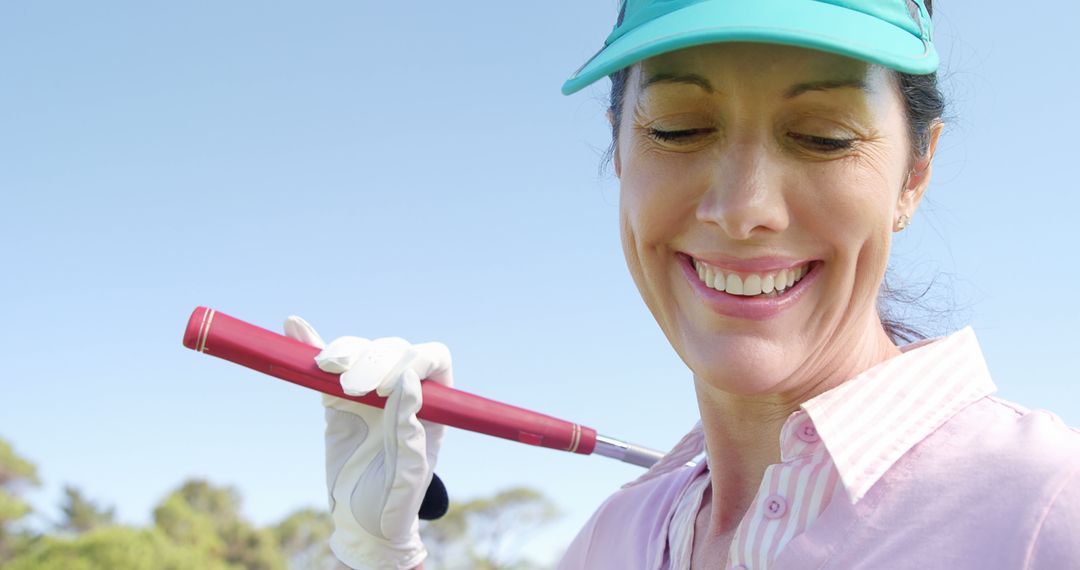 Smiling Golfer with Club Using Phone on Fairway