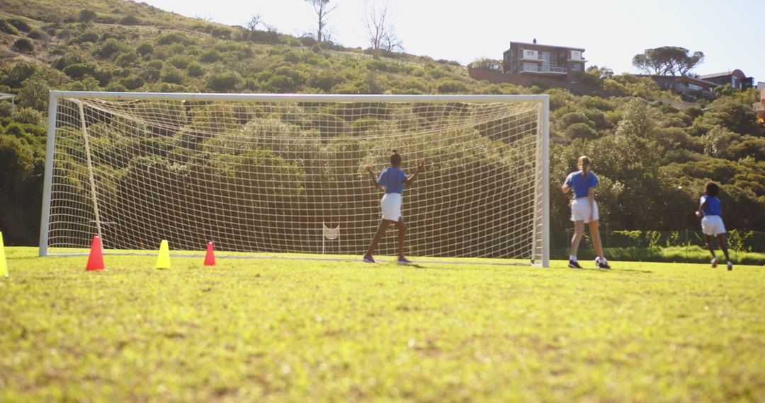 Children Practicing Soccer with Goal and Cones on Sunlit Field