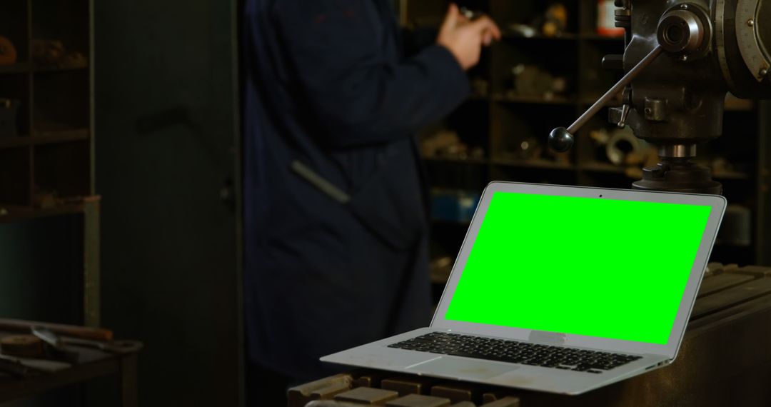 Green Screen Laptop in Industrial Workshop with Unfocused Worker - Free Images, Stock Photos and Pictures on Pikwizard.com