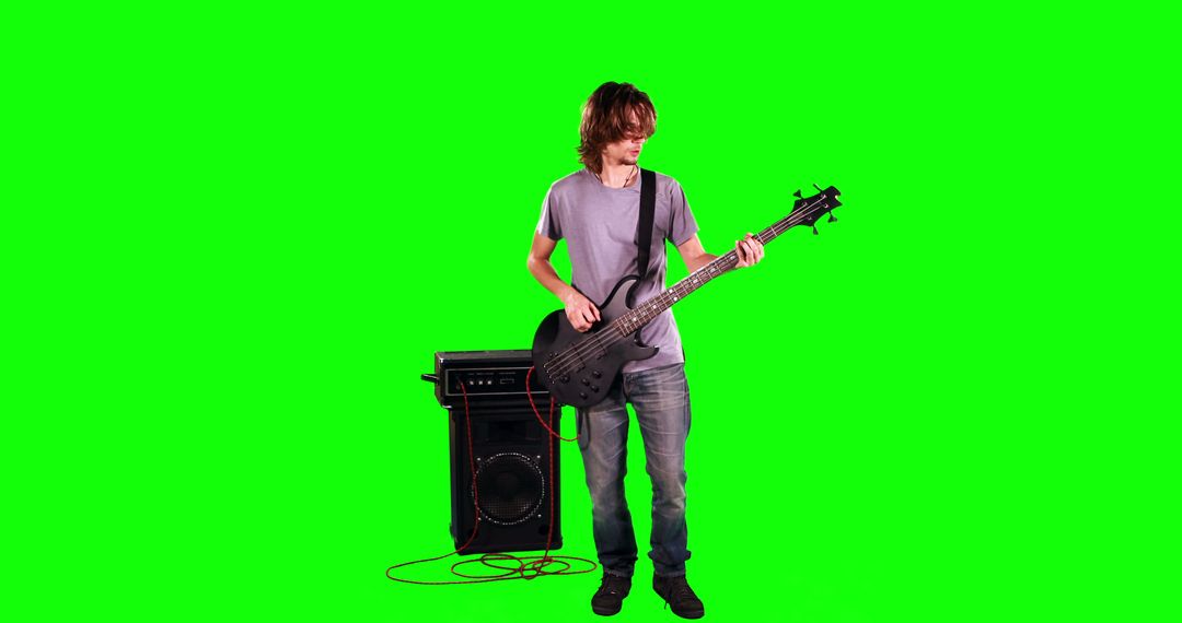 Young Man Playing Guitar Standing In Front Of Amplifier On Green Screen - Free Images, Stock Photos and Pictures on Pikwizard.com