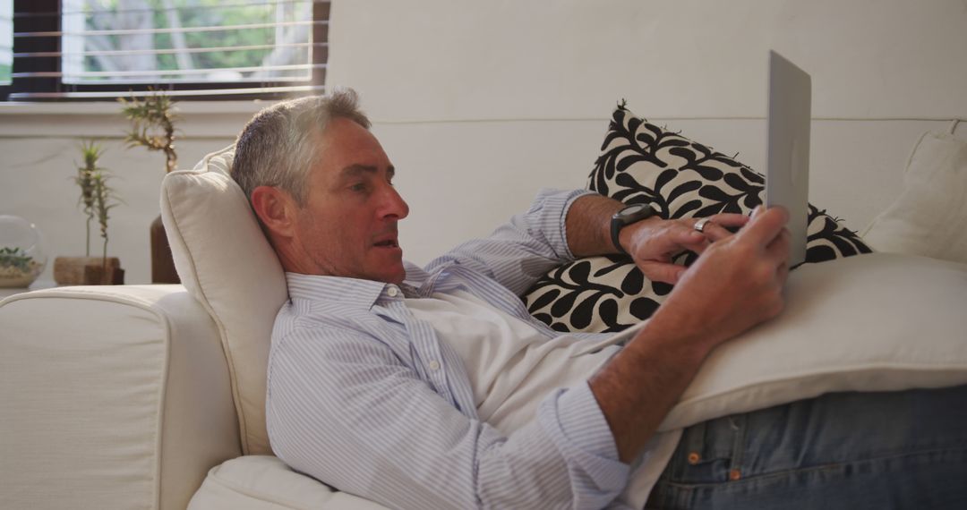 Mature Man Relaxing on Sofa with Tablet at Home - Free Images, Stock Photos and Pictures on Pikwizard.com