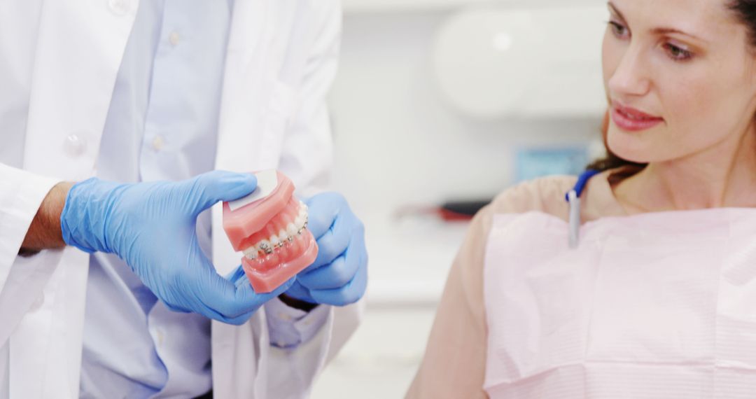 Dentist Explaining Braces to Woman Patient with Dental Model - Free Images, Stock Photos and Pictures on Pikwizard.com