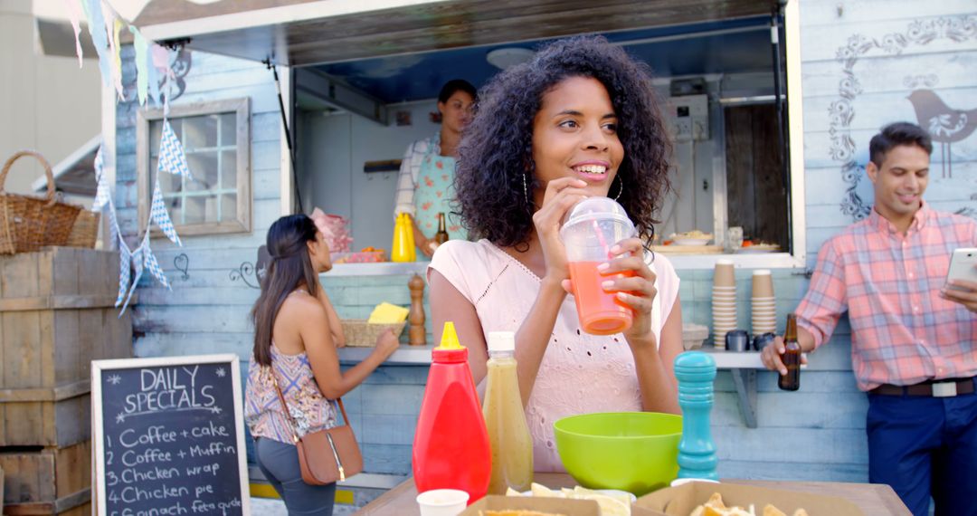 Young Woman Enjoying a Drink at a Food Truck in a Vibrant Outdoor Setting - Free Images, Stock Photos and Pictures on Pikwizard.com