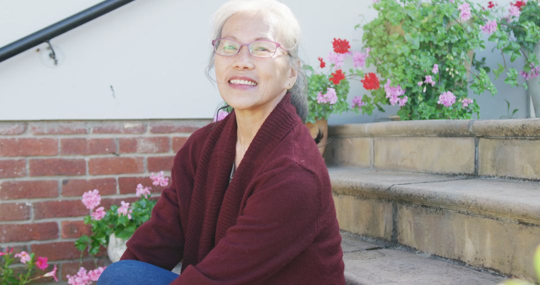 Smiling Senior Woman Sitting on Steps With Flowers - Free Images, Stock Photos and Pictures on Pikwizard.com